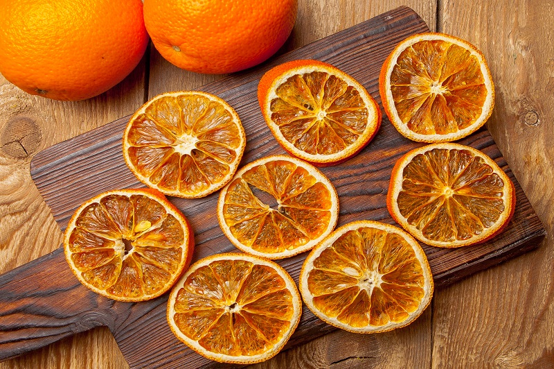 Top view dried orange on cutting board and fresh oranges on wooden table