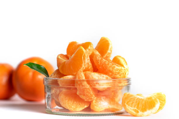 Slices of mandarins in a glass bowl on white background. With copy space