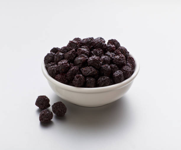 Dried cherries in a bowl on white background